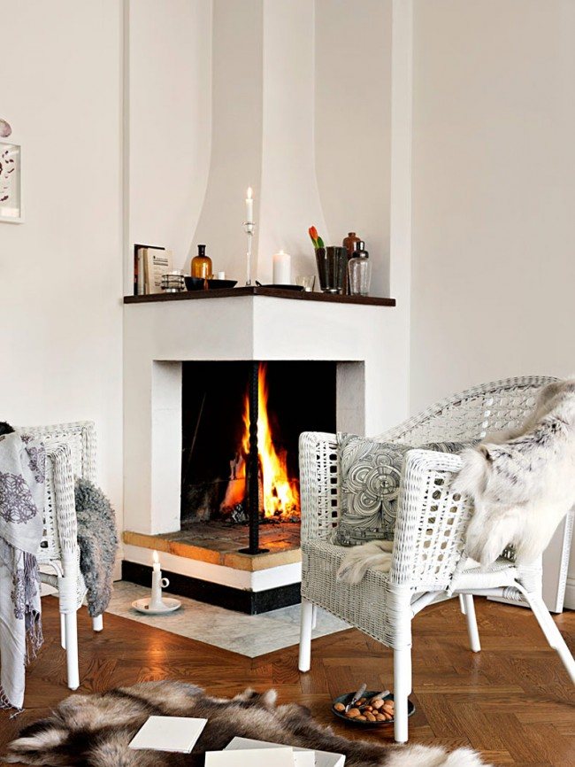 A pair of wicker chairs in front of a corner fireplace