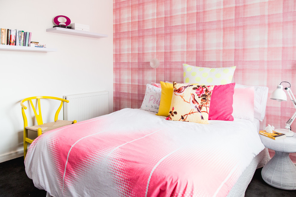 Ghế màu vàng gần giường với khăn phủ màu hồng và trắng
