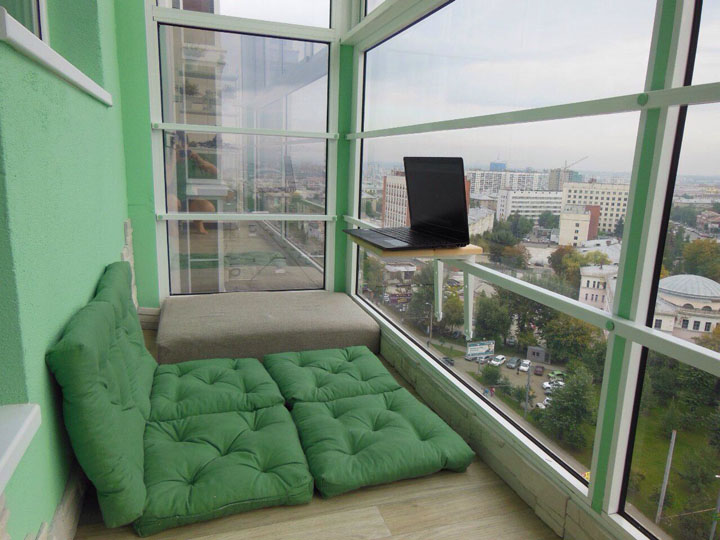 Zielone poduszki zamiast łóżek na panoramicznym balkonie