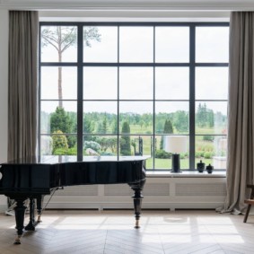 A black piano in front of a large window