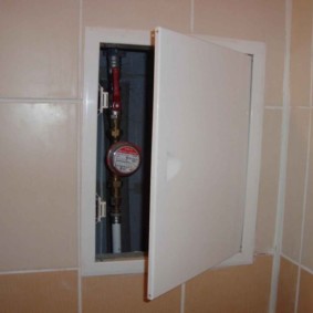 Medidor de agua detrás de la puerta entreabierta de la escotilla de fontanería