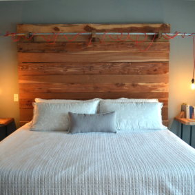 Żarówki na czerwonych sznurkach nad drewnianym łóżkiem