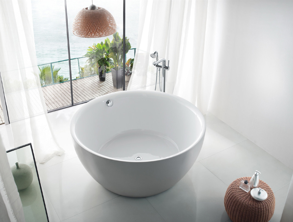 Round bathtub na gawa sa cast iron sa harap ng isang panoramic window