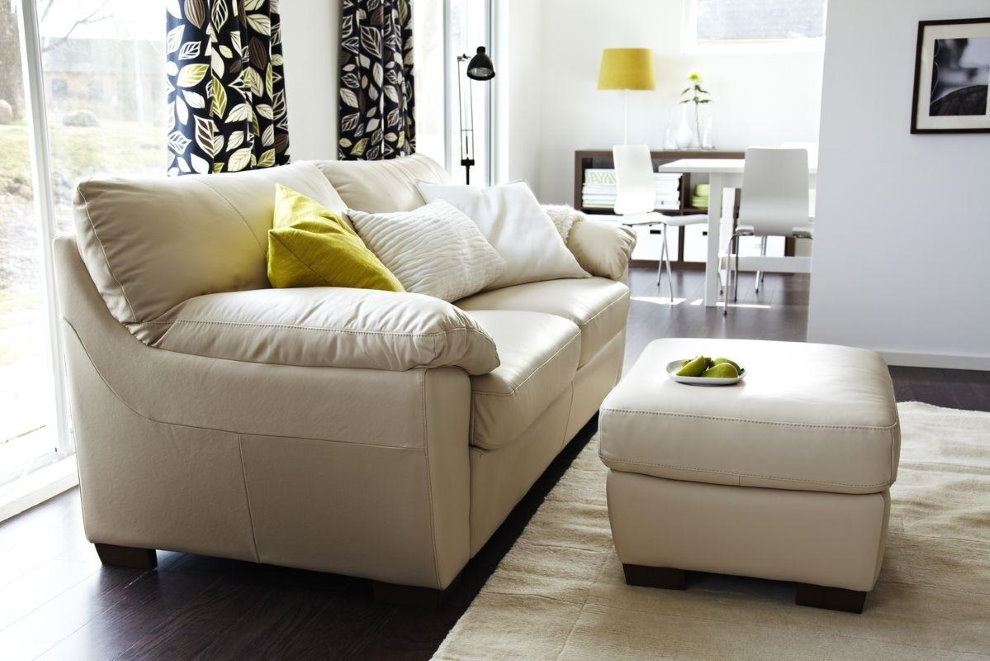 Puf con tapicería de cuero frente a un sofá en la sala de estar