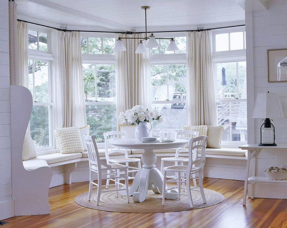 Fehér kerek asztal a nappali szoba ablakain