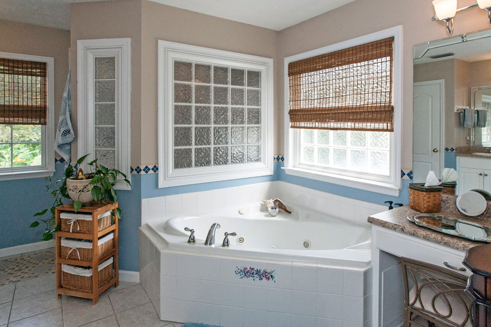 Baño de esquina de hierro fundido frente a una ventana con una cortina de bambú