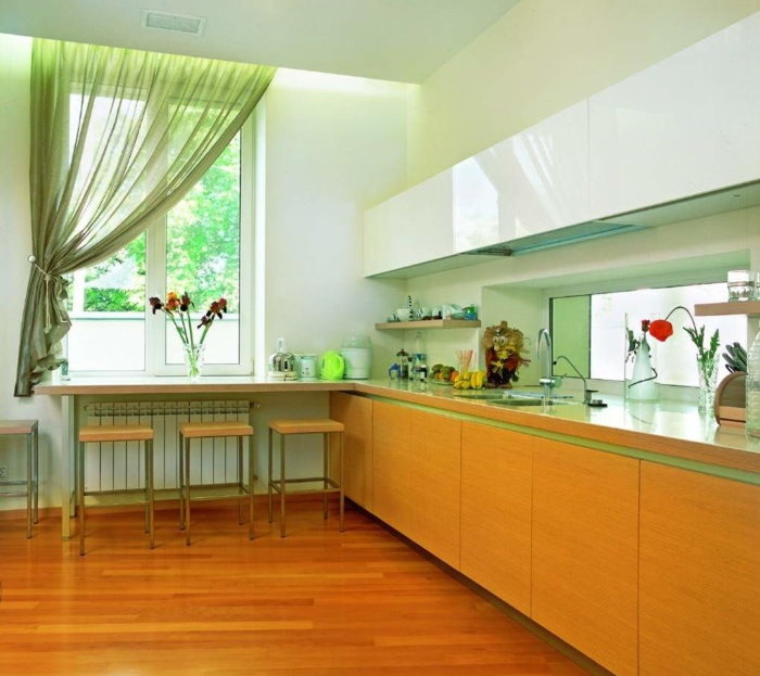 Cortina de color verd clar a un costat de la finestra de la cuina