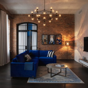 Chandelier over a blue angular sofa