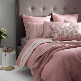 Růžové polštáře na posteli s šedou čelo