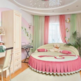 Apaļa gulta ar rozā tekstilizstrādājumu