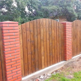 Combinația unui gard din lemn cu stâlpi din cărămidă