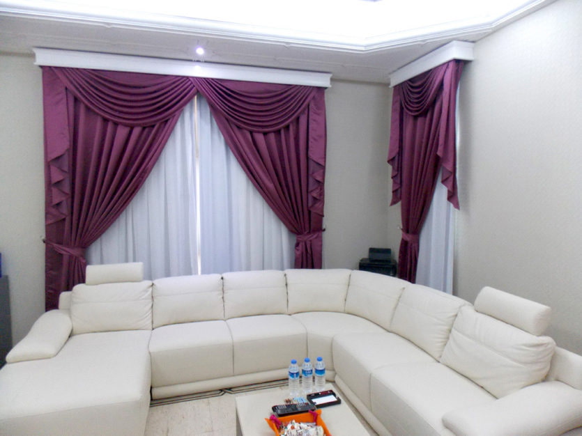 Burgundy curtains in the hall with a white sofa