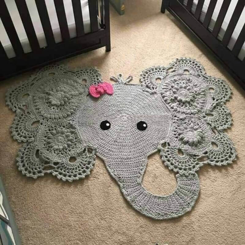Knitted rug in the shape of an elephant in front of cots