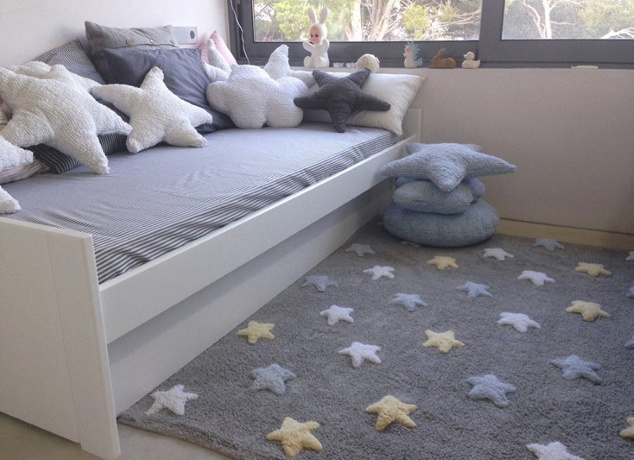Pelēks paklājs ar zvaigznēm gultiņas priekšā