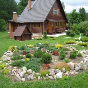 Neliels akmens dārzs uz zemes gabala ar koka māju