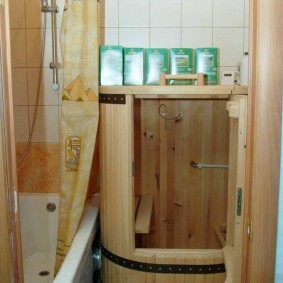 Mini-sauna in de vorm van een houten vat in de buurt van het bad