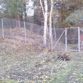 Galvanized fence on the slope of the plot
