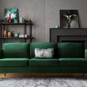 Tumši zaļš dīvāns telpā ar pelēkām sienām