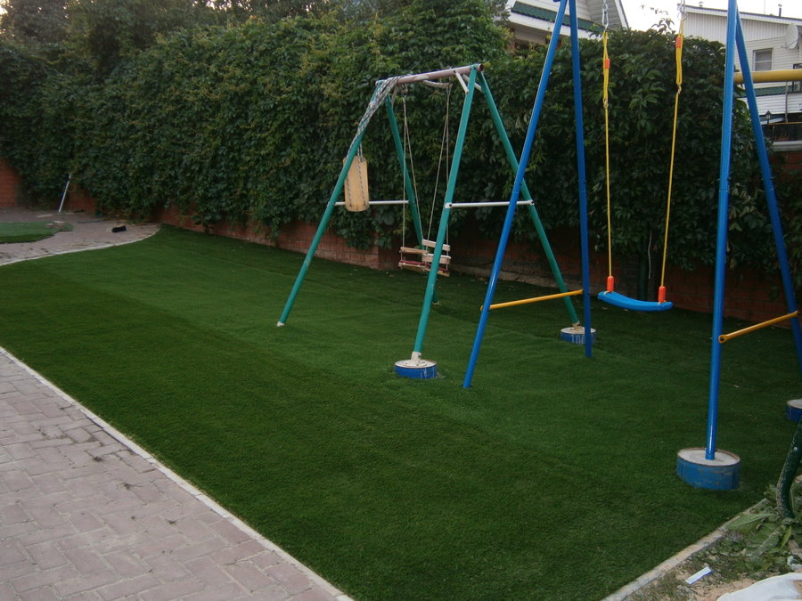 Trẻ em đu trên sân chơi với một bãi cỏ thể thao