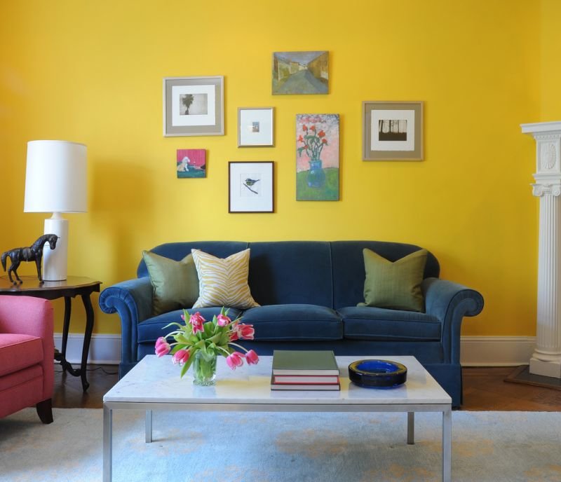 Zils dīvāns uz dzeltenas sienas fona
