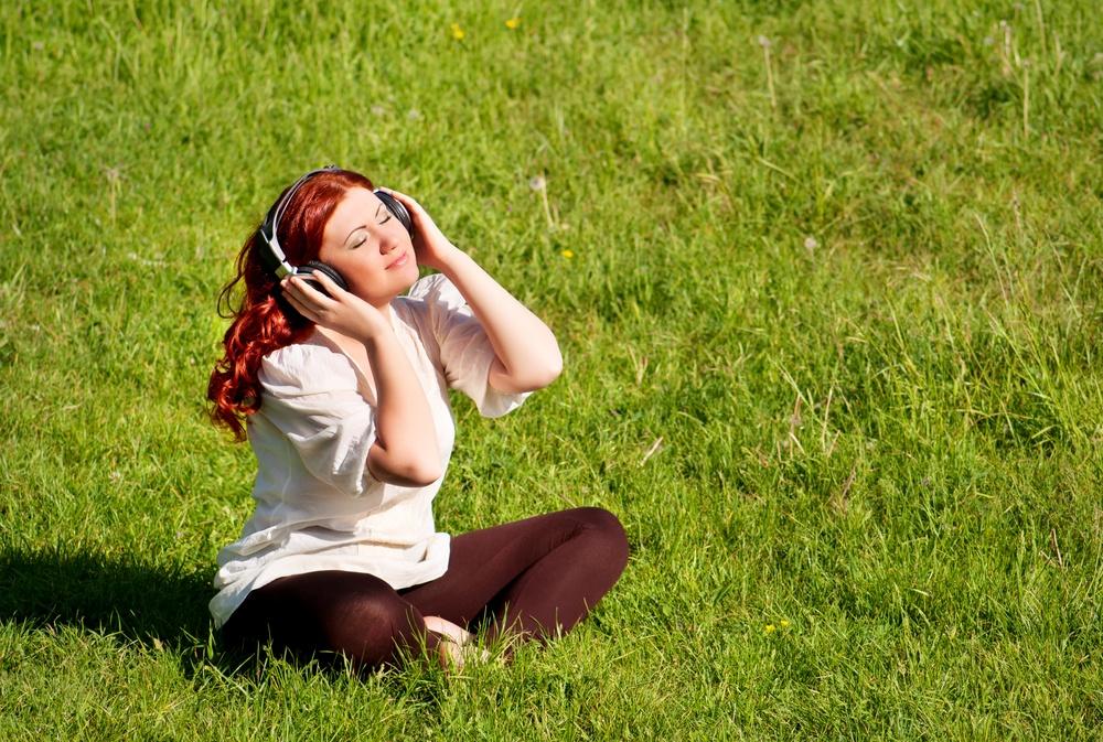 Garota em fones de ouvido em um gramado do Prado