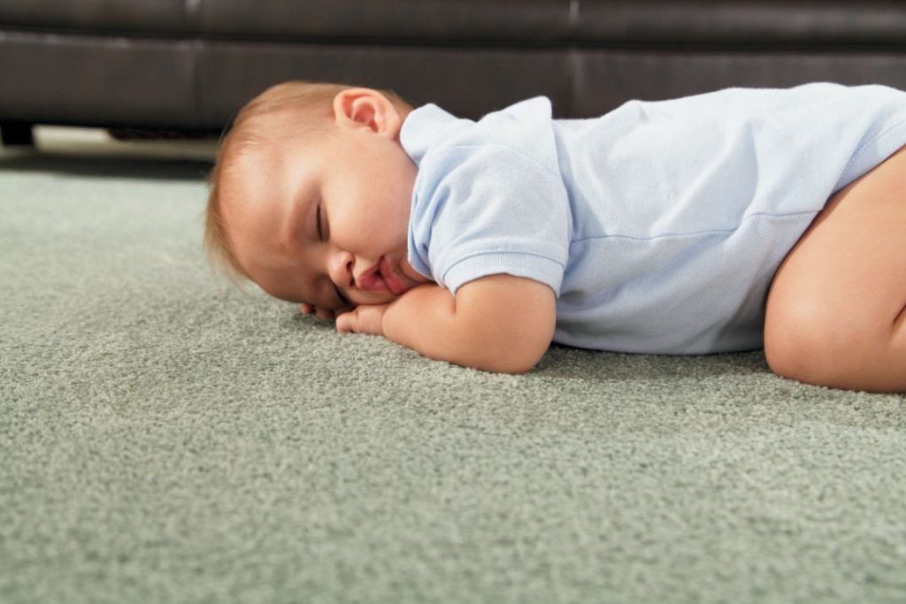 Sleeping baby on a neutral color carpet