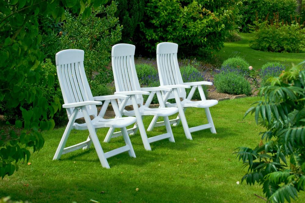 Balti dārza krēsli uz parka zāliena