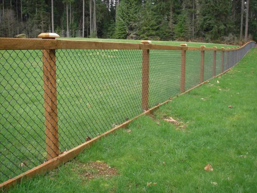 Fence of a garden site with a chain-link grid on wooden poles