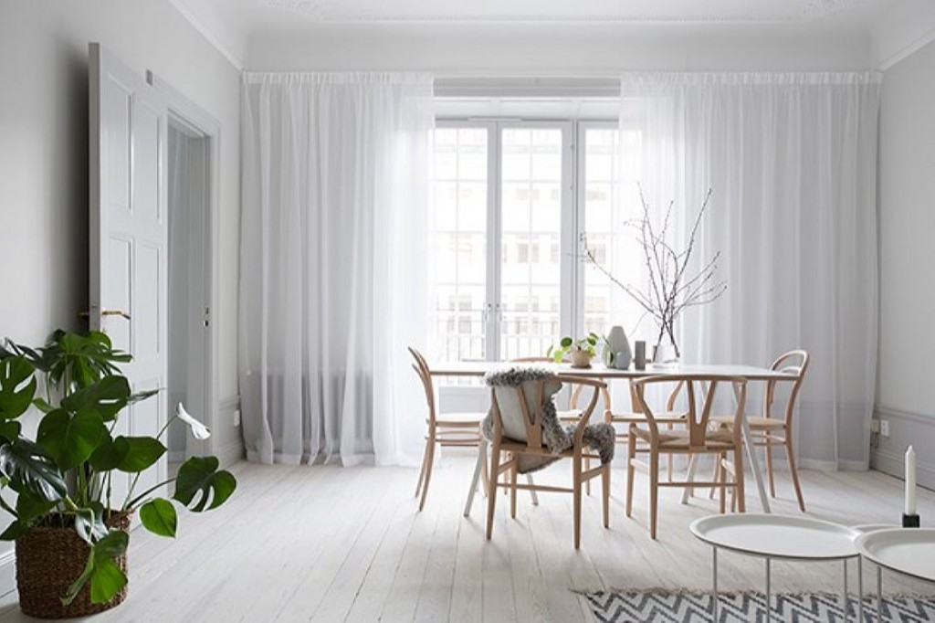 Hvite tyllgardiner på et stuevindu i skandinavisk stil