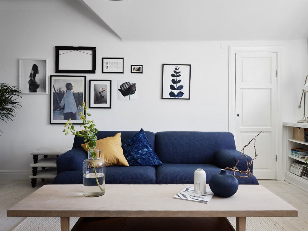 Blå sofa mot bakgrunnen til de hvite veggene i stuen