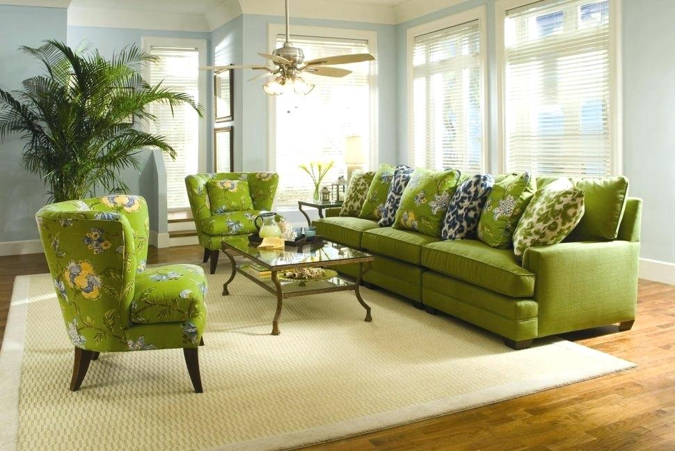 Dekoratīvi spilveni uz zaļa dīvāna zālē