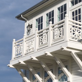 Hvit balkong på fasaden til et trehus