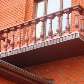 Plastmasas balkona margas ķieģeļu mājā