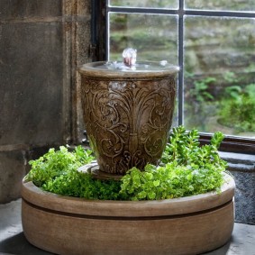 Dekoratyvinis fontanas su gyvais augalais ant buto palangės