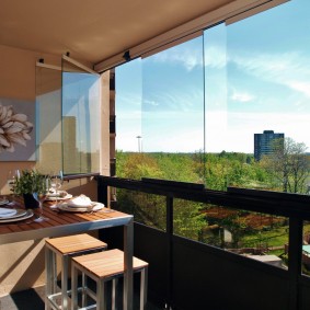 Eettafel op het balkon met frameloze beglazing