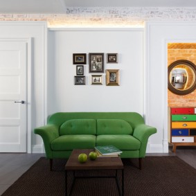 Zielona kanapa przy białej ścianie salonu