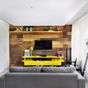 Żółte meble na drewnianej ścianie salonu