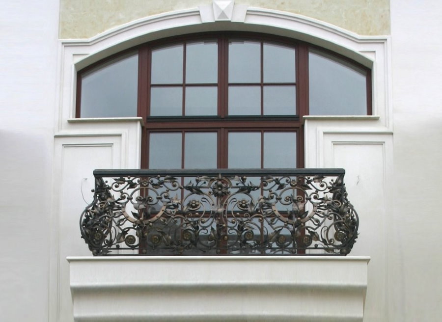 Balustrada forjată pe balconul casei cu pereți albi