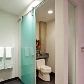 Toaleta montată pe podea în spatele unei pereți despărțitori de sticlă